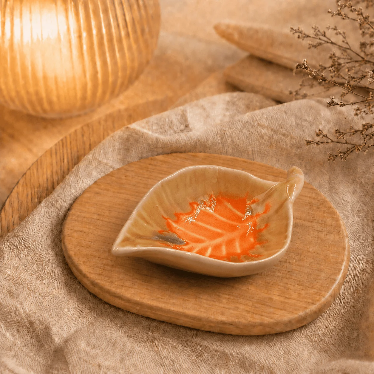 Beige bladvormig schaaltje met oranje decoratie op houten plank